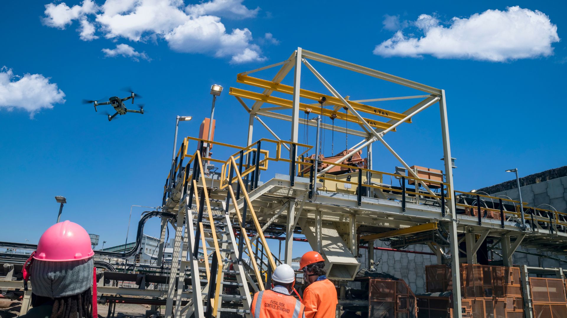 Drone flying over industrial site with workers in safety gear